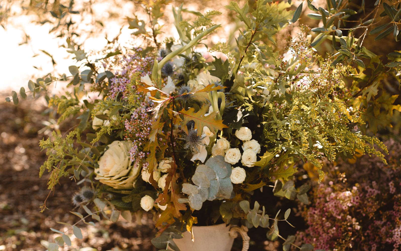 Composición floral de ATEMP sobre un pedestal, bajo un olivo